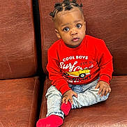 Aboubakar Khalil a rejoint le concours — aidez-le/la à gagner de superbes lots ! toddler, child, boy, red_sweater, jeans, red_socks, brown_leather_couch, sitting, indoor, curious_expression, portrait, hairstyle, bantu_knots, casual_clothing, young_child, cute, fashion, hands, feet, person