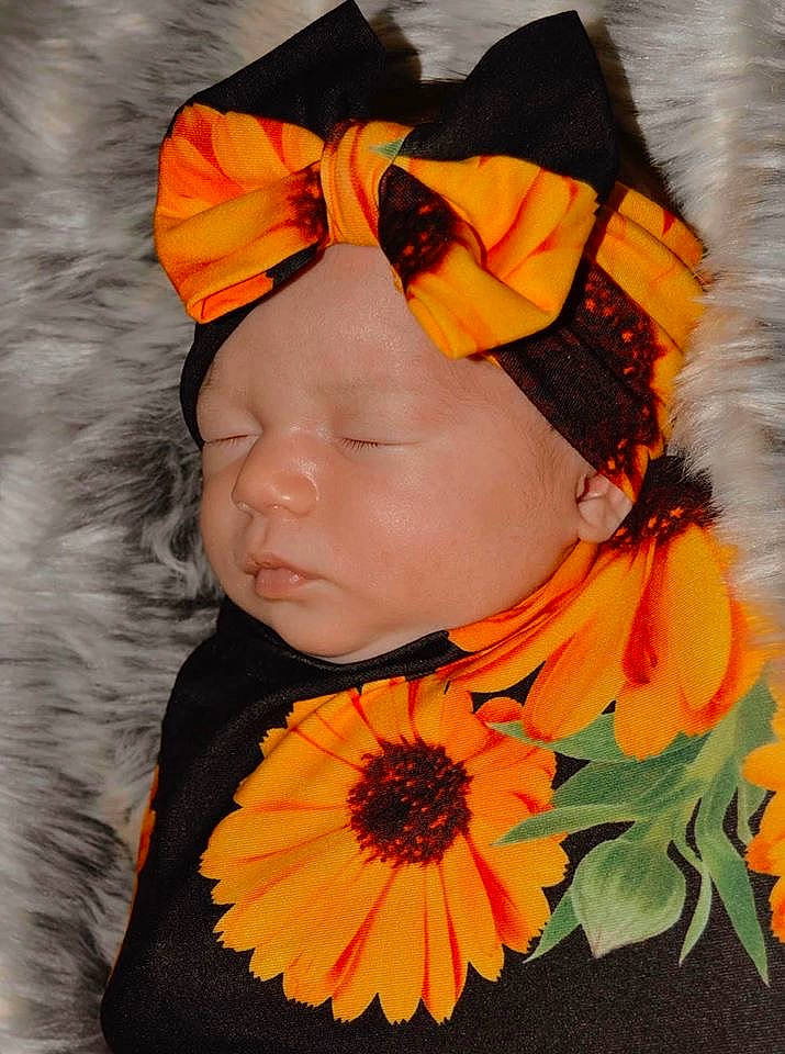 Journee is registered to the contest to win money with this photo: baby, candy_corn, child, costume, costume_accessory, flower, hair_accessory, headband, headgear, orange, person, plant, sunflower, toddler