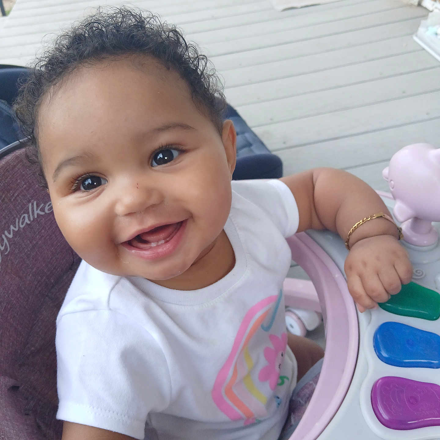 Makeya is registered to the contest to win money with this photo: baby, bracelet, child, closeup, curly_hair, cute, flower, happy, infant, person, piano, playful, porch, rainbow, seat, smiling, toy, tshirt, walker, wooden_floor