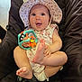 baby, child, hat, floral, toy, smiling, happy, cute, sitting, cushion, chair, clothing, face, hands, feet, indoor, infant, playful, portrait, person