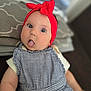 Lilianna is registered to the contest to win money with this photo: baby, infant, headband, red_bow, tongue_out, blue_eyes, checkered_outfit, blanket, indoor, cute, child, portrait, playful, clothing, soft_light, face, person, young_child, expression, closeup