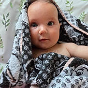 Lilianna is registered to the contest to win money with this photo: baby, towel, face, eyes, skin, blanket, pattern, bedspread, leaf, indoor, child, person, portrait, cute, infant, resting, soft, cozy, expression, young