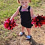 toddler, child, pacifier, pom_poms, cheerleader, grass, outdoor, sandals, black_dress, sunlight, shadow, cute, fun, play, summer, young_child, person, pigtails, happy, standing