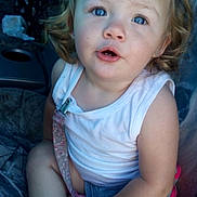 Victoria is registered to the contest to win money with this photo: child, toddler, blue_eyes, curly_hair, white_tank_top, shoe, sitting, vehicle_interior, seat, hand, face, expression, hair_ties, clothing, cute, baby, young_child, seat_cover, casual, indoor