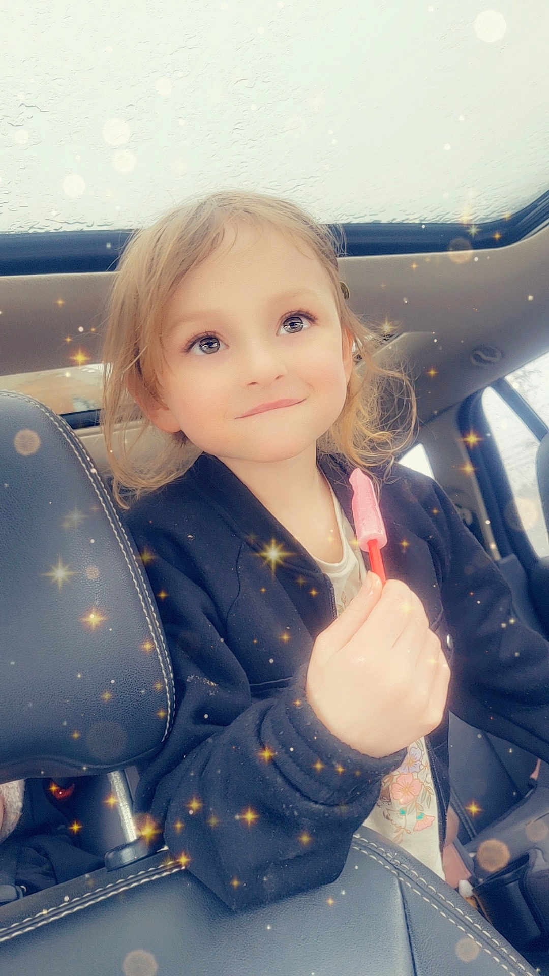 Kennedy joined the competition — help win amazing prizes! child, car, seat, popsicle, smile, sparkles, magic_effect, window, jacket, hair, face, happy, indoors, portrait, cute, young, holding, hand, seatbelt, light