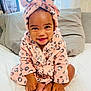 baby, child, smiling, pink, robe, headband, bow, leopard_print, bed, pillow, curtain, indoors, cute, happy, infant, person, skin, foot, hand, sitting
