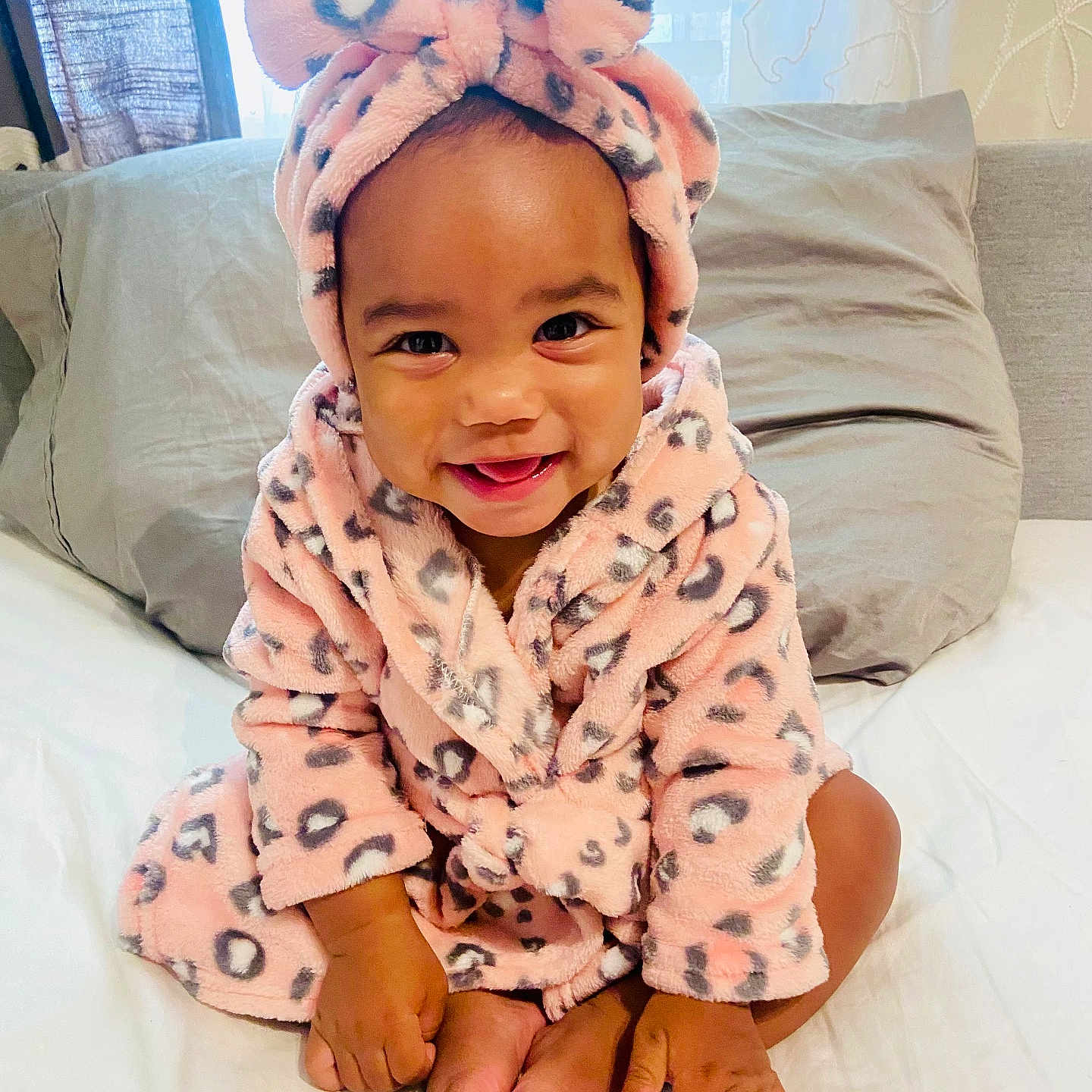 Milli Lorraine is registered to the contest to win money with this photo: baby, bed, bow, child, curtain, cute, foot, hand, happy, headband, indoors, infant, leopard_print, person, pillow, pink, robe, sitting, skin, smiling