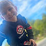 Tiago a rejoint le concours — aidez-le/la à gagner de superbes lots ! child, boy, smiling, outdoor, sky, clouds, hoodie, pants, mario, cartoon, casual_clothing, happy, young, person, nature, daylight, park, playful, portrait, blue_sky