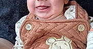 Michael is registered to the contest to win money with this photo: baby, smile, face, infant, clothing, winnie_the_pooh, quilted, button, hand, tongue, person, cute, happy, cartoon, dr_pepper, dark_background, sleeve, pattern, closeup, portrait