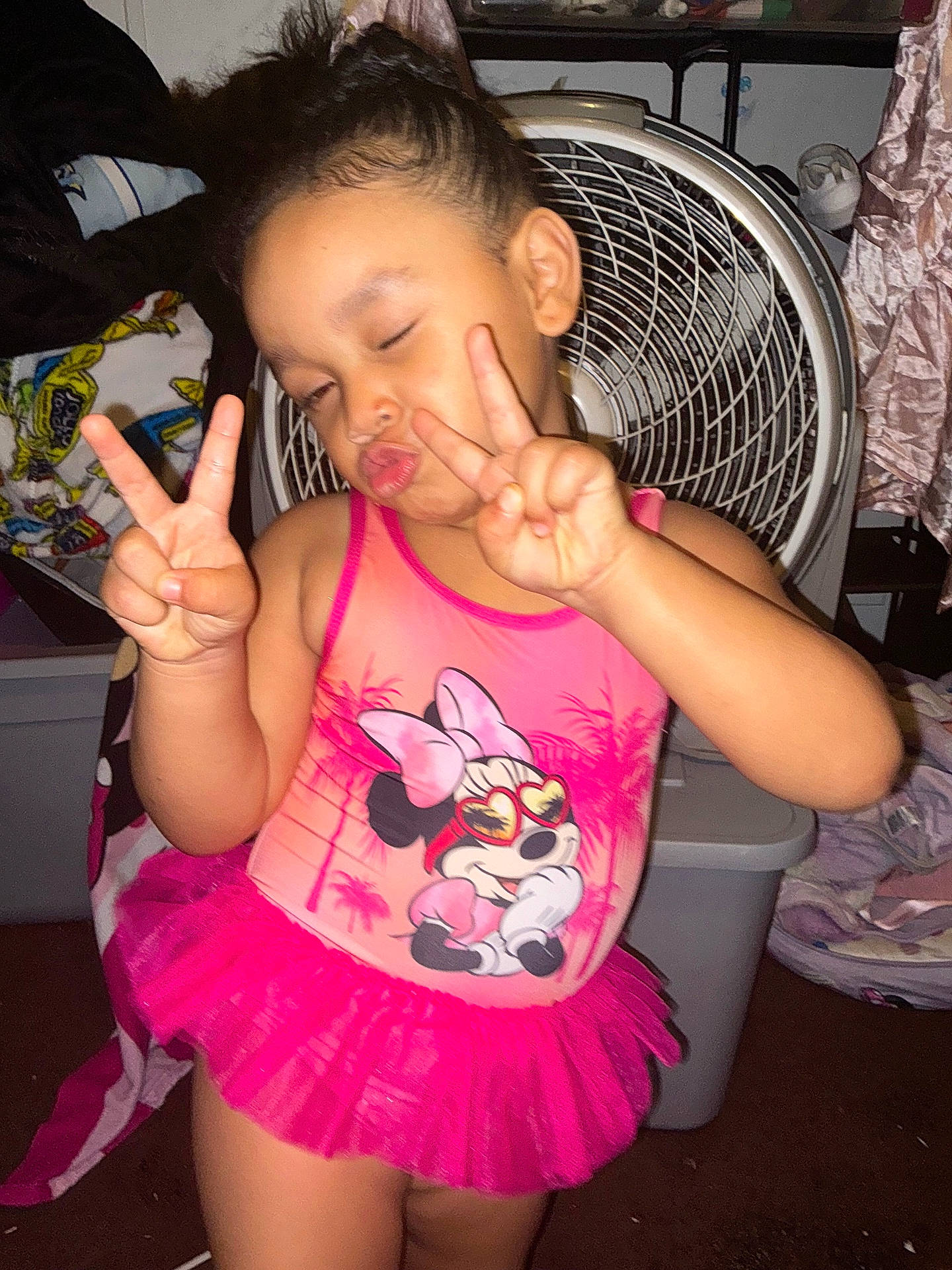 Bloom is registered to the contest to win money with this photo: casual, child, clothing, cute, expression, fan, fashion, fun, girl, household, indoor, minnie_mouse, peace_sign, person, pink, playful, posing, room, smiling, tutu