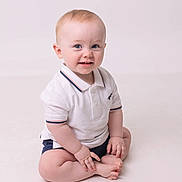 Joshua joined the competition — help win amazing prizes! baby, child, infant, smiling, sitting, white_polo, shorts, blue_eyes, cute, portrait, studio, light_background, hands, feet, happy, toddler, skin, face, young, indoors