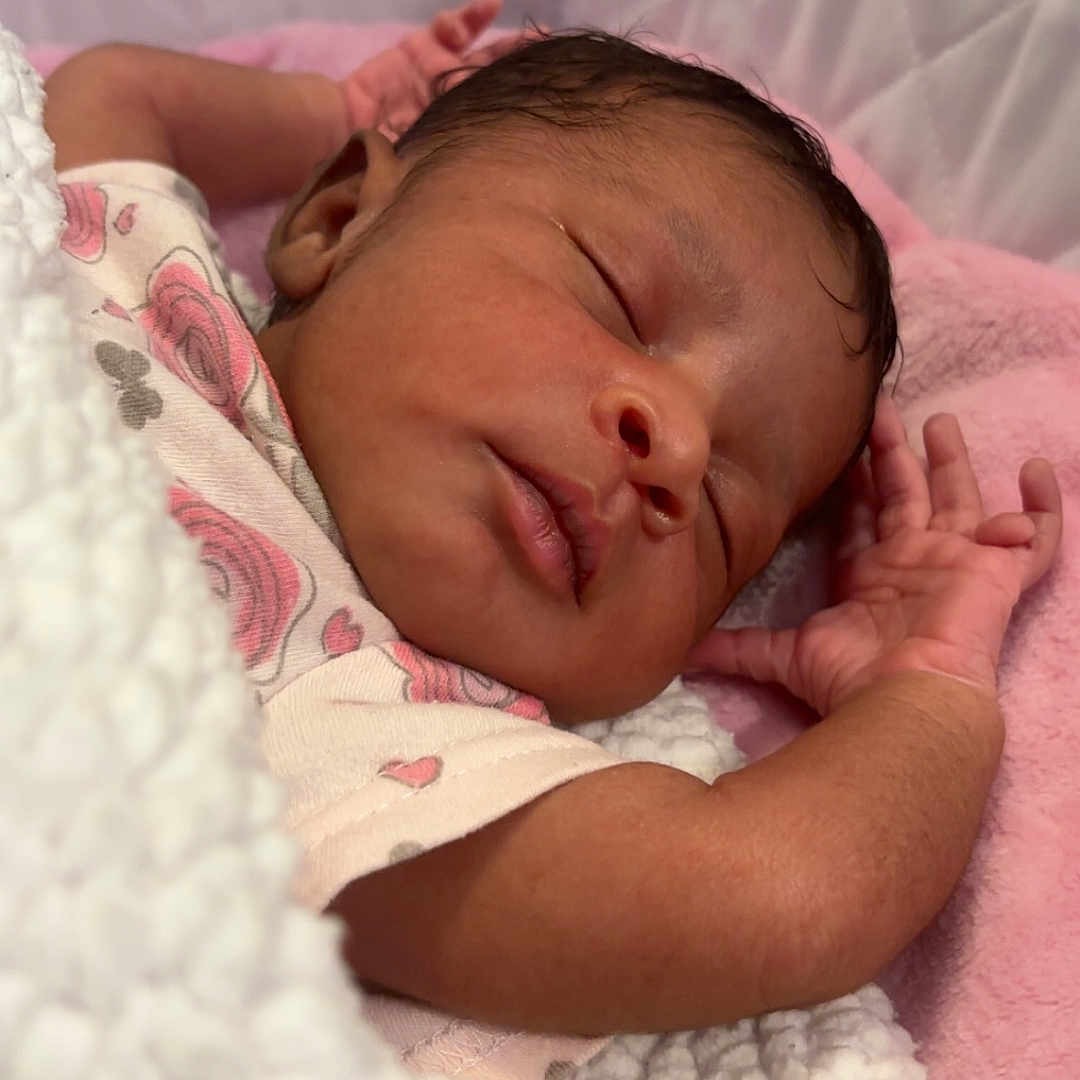 Naomi is registered to the contest to win money with this photo: baby, bed, blanket, cozy, cute, face, floral_pattern, hand, infant, newborn, onesie, peaceful, pink, portrait, quilted, rest, skin, sleeping, soft, white