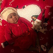 Anna Joëlle participe au concours pour gagner de l'argent avec cette photo : baby, infant, red_clothing, white_hat, christmas_blanket, holiday_decor, santa_ornament, noel_sign, festive, cute, indoors, blanket, christmas, child, face, smile, toddler, warm_lighting, cozy, holiday