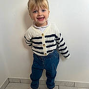 Ambre participe au concours pour gagner de l'argent avec cette photo : child, girl, blonde_hair, blue_eyes, smiling, white_wall, striped_sweater, denim_pants, white_sneakers, standing, indoor, happy, casual_clothing, earrings, tile_floor, portrait, cute, young_child, fashion, playful