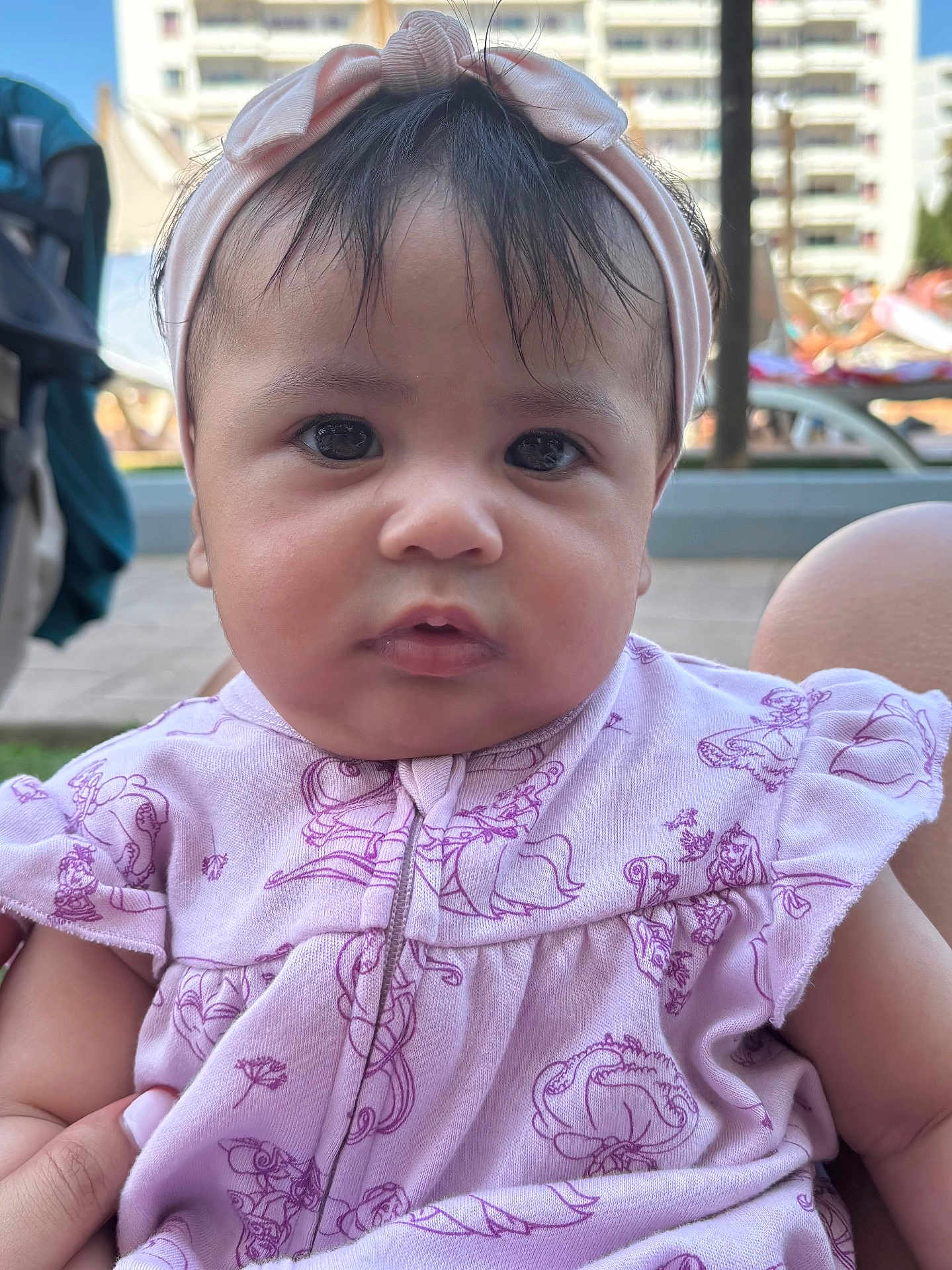 Aida a rejoint le concours — aidez-le/la à gagner de superbes lots ! baby, infant, child, portrait, close_up, headband, pink_clothing, outdoor, curious, face, eyes, skin, person, cute, young, sitting, hand, background, daylight, expression