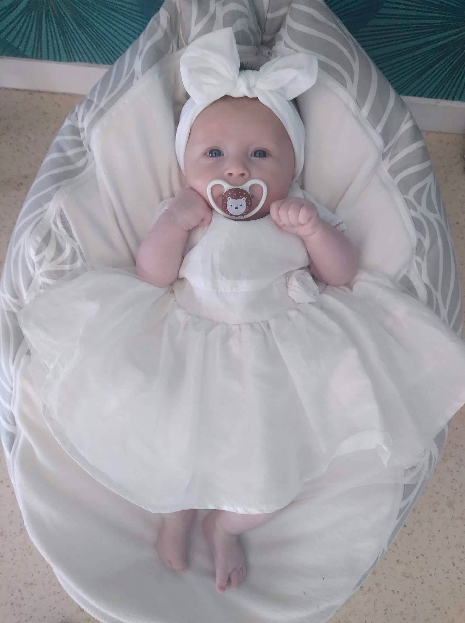 Chelsea participe au concours pour gagner de l'argent avec cette photo : baby, baby_products, baby_toddler_clothing, bridal_accessory, cheek, child, comfort, dress, event, eye, fashion_accessory, hair, happy, headgear, headwear, human_body, iris, linens, person, pink