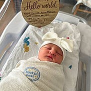 Brielle is registered to the contest to win money with this photo: newborn, baby, swaddled, blanket, hat, bow, sleeping, hospital, bassinet, plaque, wooden, text, infant, cute, peaceful, face, person, bed, towel, soft