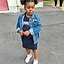 casual_clothing, child, daylight, denim_jacket, expression, footwear, girl, hair_style, jacket, outdoor, pavement, people_in_background, person, pigtails, pink_sneakers, sidewalk, standing, street, trees, urban