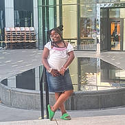 Alihya participe au concours pour gagner de l'argent avec cette photo : child, girl, glasses, braided_hair, green_slippers, denim_skirt, white_shirt, bracelets, urban, modern_building, glass_windows, reflection, chairs, outdoor, daylight, pose, smile, casual, fashion, sidewalk