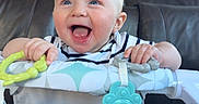 Silas joined the competition — help win amazing prizes! baby, smiling, blue_eyes, toy, baby_seat, indoor, living_room, furniture, happy, infant, child, clothing, foot, hand, face, person, couch, teether, striped_shirt, playtime