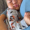 Armaan is registered to the contest to win money with this photo: baby, sleeping, infant, child, portrait, close_up, face, cozy, cuddling, adult, arms, blue_sweater, onesie, cartoon, halloween, mickey_mouse, patterned_clothing, bottle, indoors, peaceful