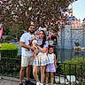 Armaan is registered to the contest to win money with this photo: family, child, baby, girl, parents, theme_park, castle, flowering_tree, outdoor, portrait, smiling, standing, pavement, pond, garden, amusement_park, sunglasses, headband, colorful_clothing, vacation