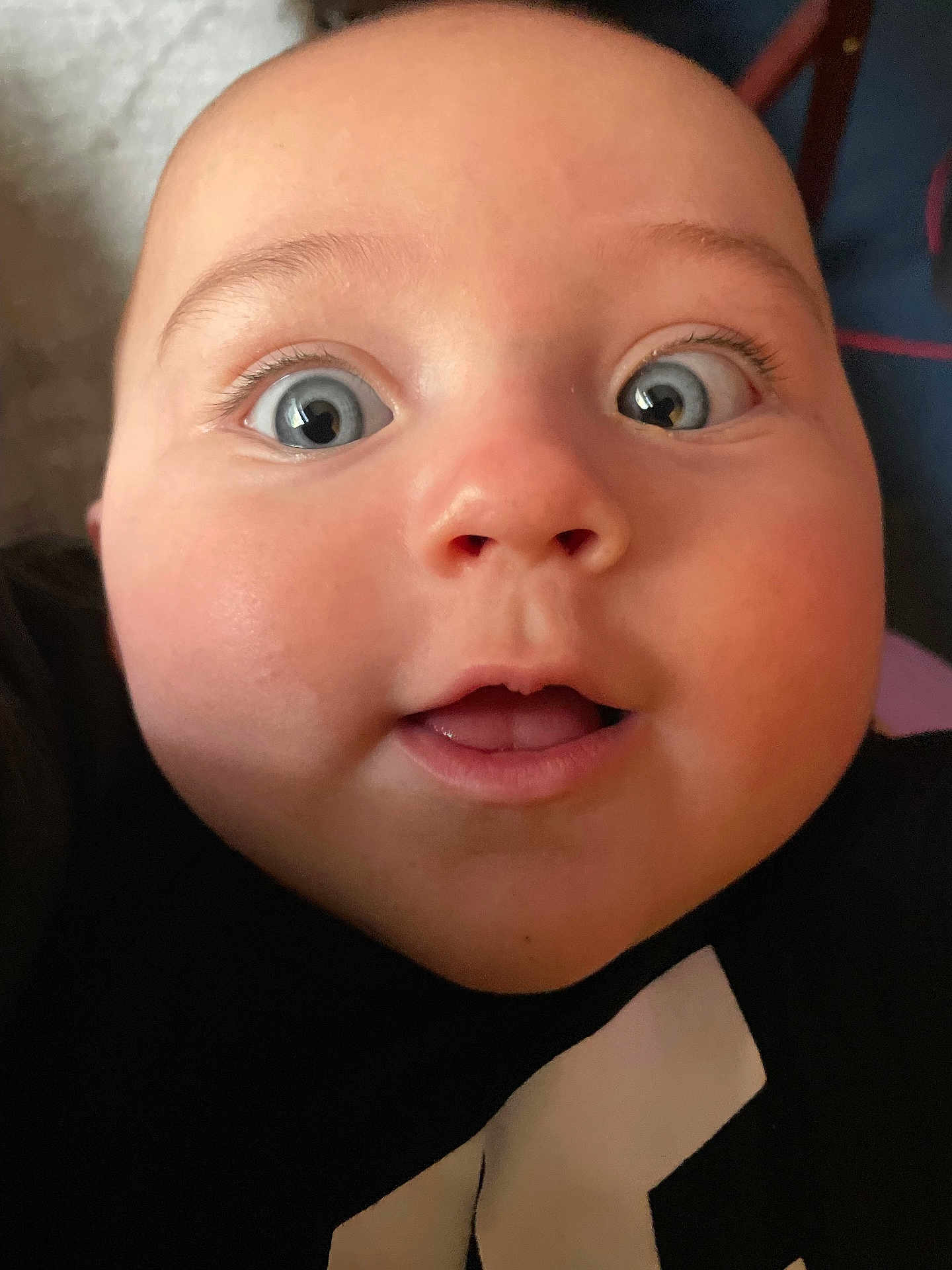 Jameson is registered to the contest to win money with this photo: baby, face, close_up, blue_eyes, expression, chubby_cheeks, innocence, curiosity, portrait, skin, mouth, eyelashes, person, child, head, black_clothing, indoors, cute, human, young