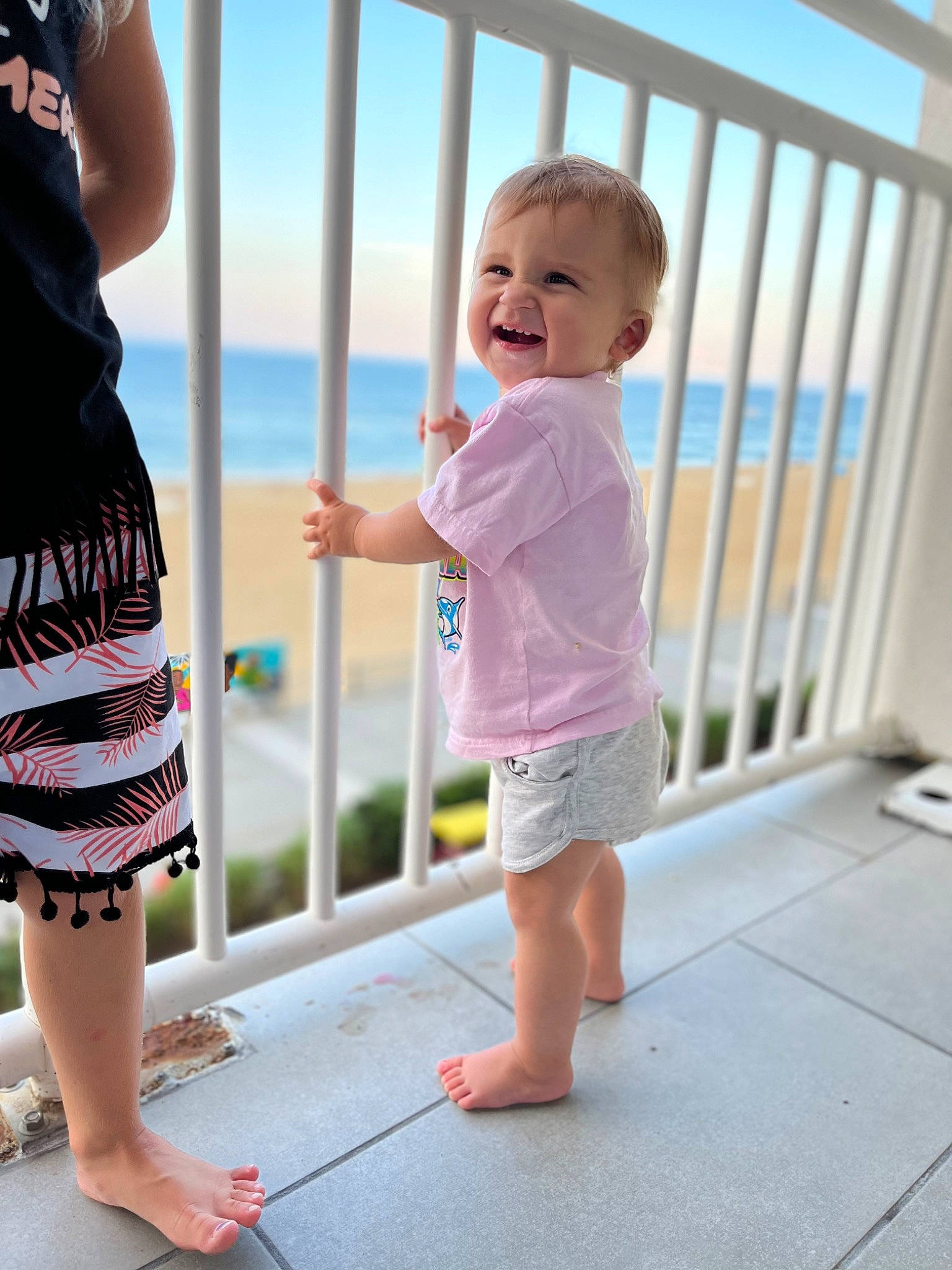 Emerleigh is registered to the contest to win money with this photo: baby, baby_toddler_clothing, clothing, fence, fun, gesture, happy, joint, joy, person, pink, product, shorts, skin, sky, sleeve, smile, standing, summer, thigh