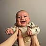 Danny is registered to the contest to win money with this photo: baby, smiling, hands, feet, playful, happy, infant, person, face, expression, clothing, indoors, adult, joy, cute, skin, head, background, light, fun
