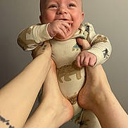 Danny joined the competition — help win amazing prizes! baby, infant, smiling, happy, onesie, animal_print, hands, feet, playful, child, person, indoor, neutral_background, cute, joyful, skin, holding, expression, portrait, casual