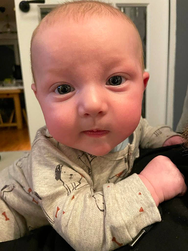 Archie is registered to the contest to win money with this photo: baby, baby_toddler_clothing, cheek, child, curtain, ear, eyebrow, eyelash, fun, iris, jaw, lip, mouth, nose, person, shelf, sitting, skin, sleeve, thumb