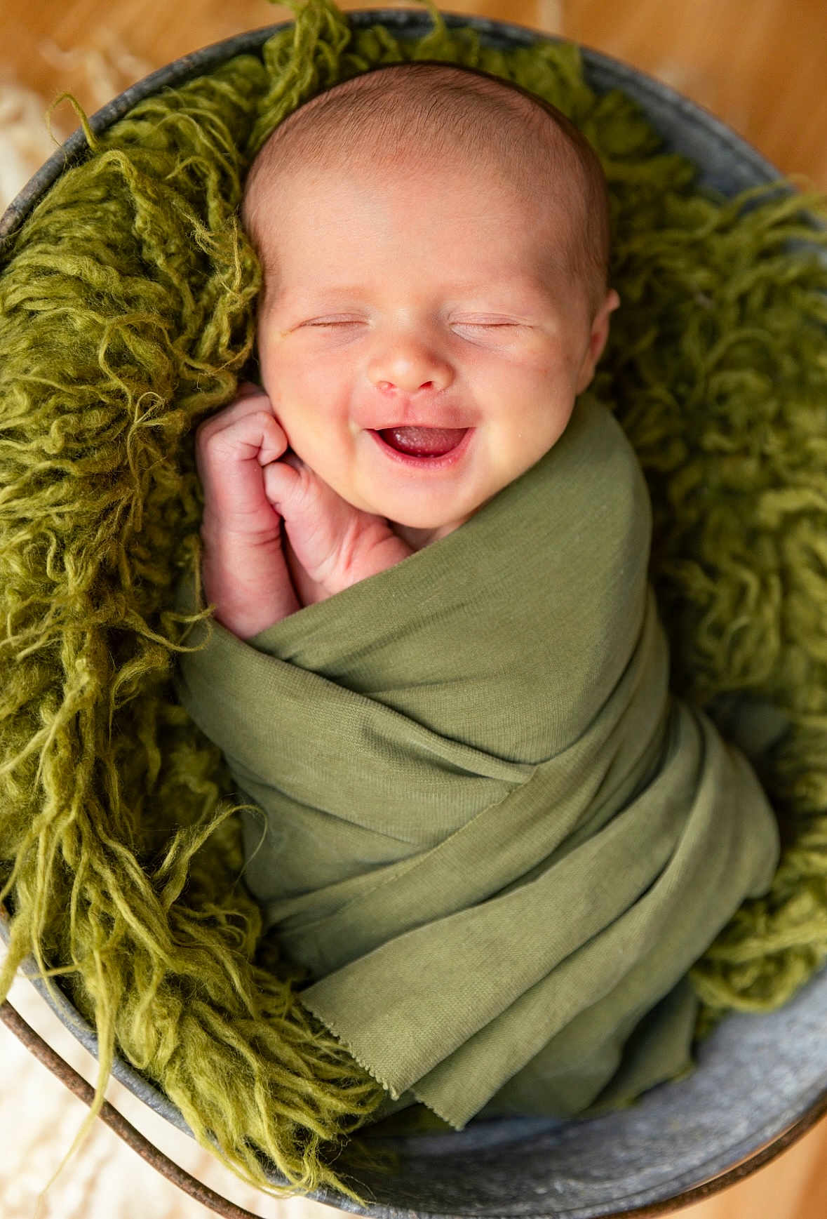 August joined the competition — help win amazing prizes! baby, infant, swaddled, green_cloth, smiling, closed_eyes, basket, fuzzy_blanket, newborn, cute, sleeping, portrait, soft_texture, cozy, happy, small_hands, head, face, indoors, peaceful