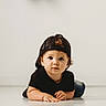 child, toddler, baby, portrait, studio, floor, lying_down, backwards_cap, black_clothing, casual, curly_hair, brown_hair, face, eyes, hands, crawling, fashion, indoor, minimalist, photography