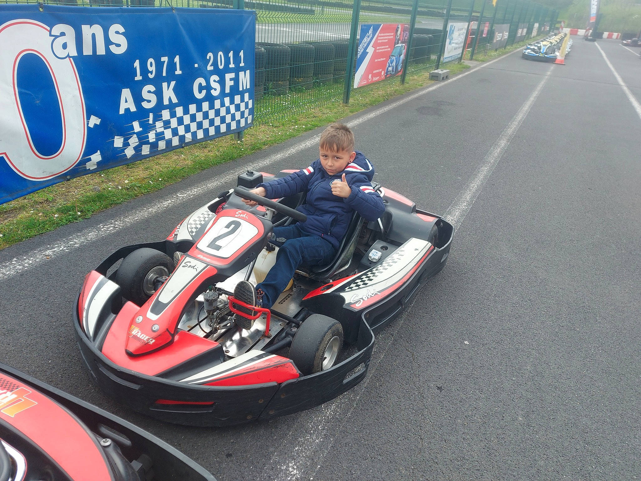 Lookas a rejoint le concours — aidez-le/la à gagner de superbes lots ! asphalt, auto_racing, automotive_design, automotive_exterior, automotive_tire, automotive_wheel_system, car, helmet, motor_vehicle, motorcycle_helmet, motorsport, person, personal_protective_equipment, race_track, racing, rim, sports, sports_gear, tire, vehicle