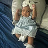 Nova is registered to the contest to win money with this photo: baby, infant, child, blue_dress, headband, bow, pillow, bed, blanket, socks, raising_arms, cute, sleepwear, indoors, person, portrait, young_child, fabric, soft, happy