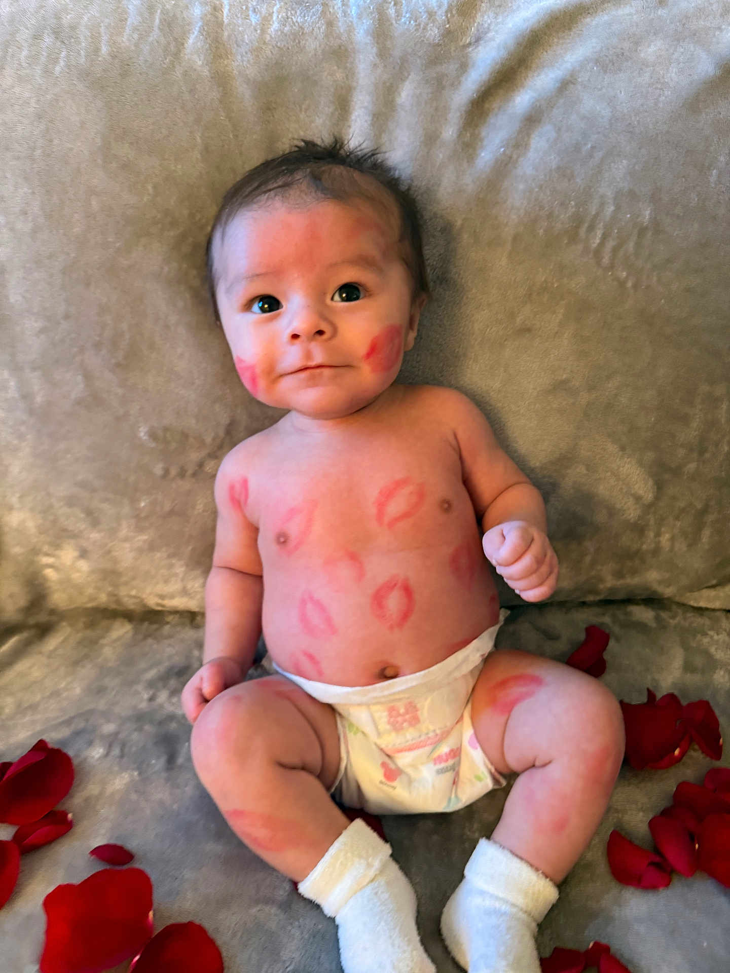 Roland is registered to the contest to win money with this photo: baby, infant, newborn, diaper, socks, rose_petals, lipstick_kiss_marks, kiss_marks, cheeks, face, eyes, smile, torso, arms, legs, soft_blanket, couch, portrait, indoor, playful