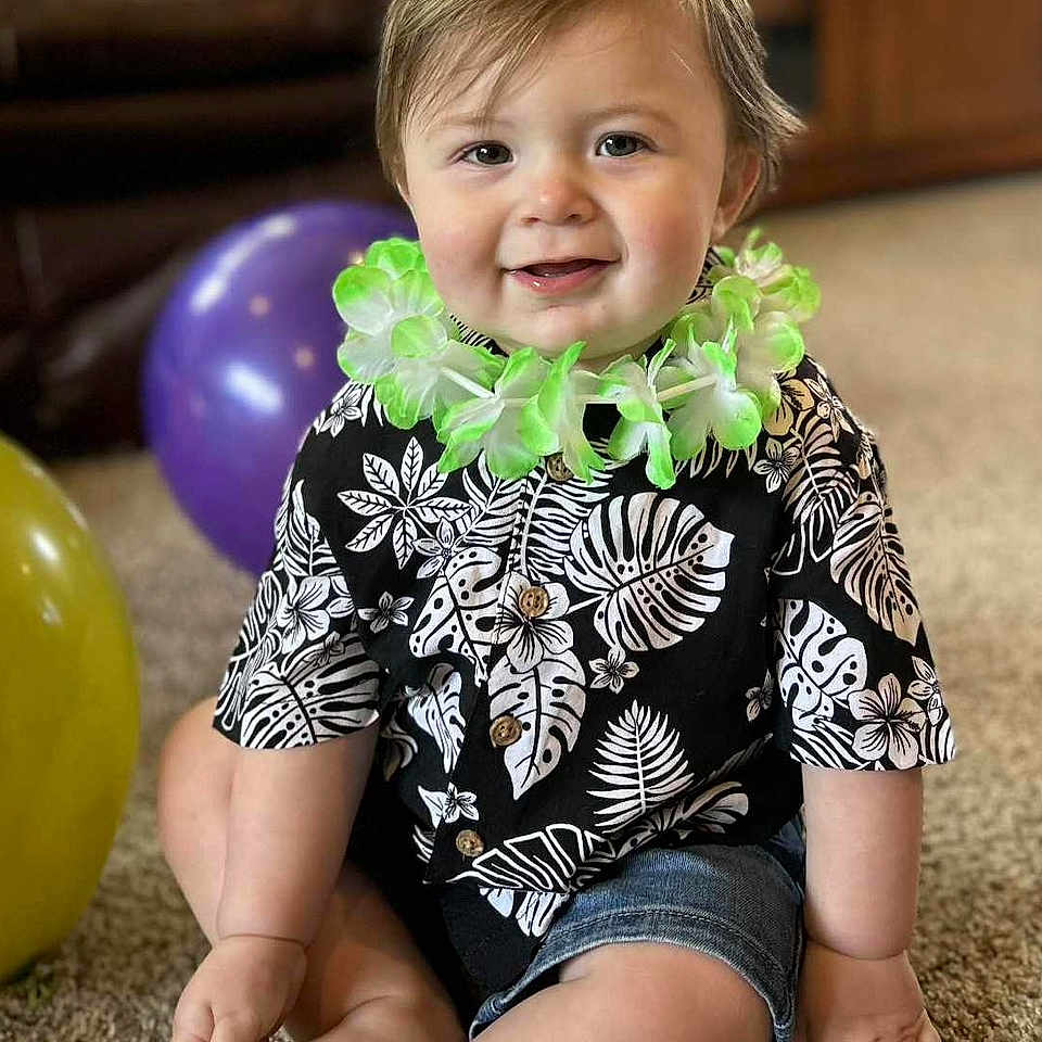 Oli-Ray joined the competition — help win amazing prizes! baby, balloon, candid, carpet, celebration, child, cute, decor, feet, flower_lei, hands, happy, indoor, person, portrait, shirt, shorts, sitting, smiling, toddler