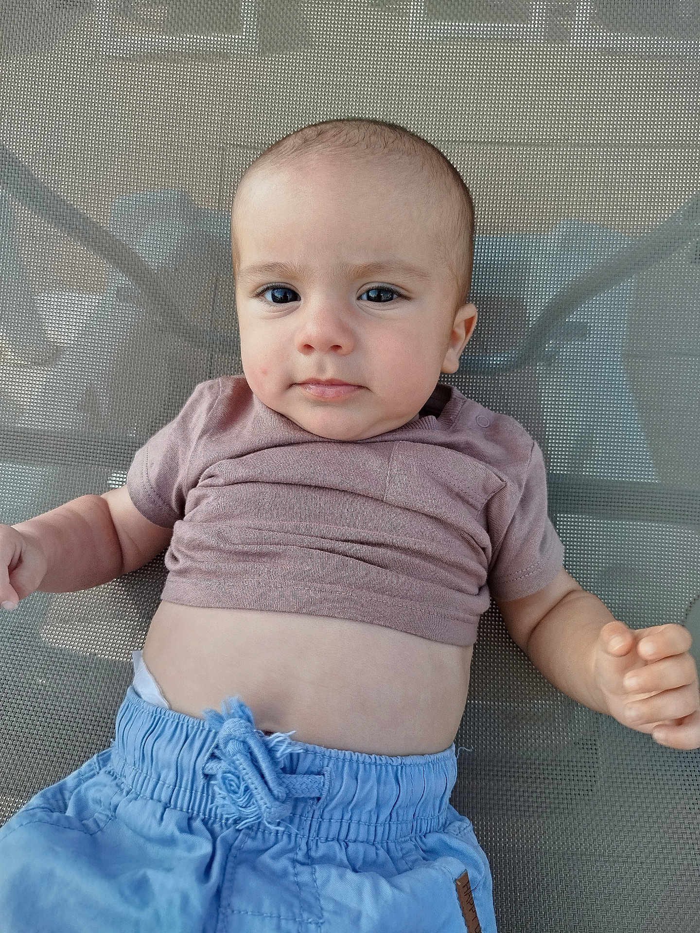 Leo participe au concours pour gagner de l'argent avec cette photo : baby, child, face, eyes, shirt, shorts, mesh_chair, hand, skin, expression, casual_clothing, infant, portrait, sitting, indoors, young_child, cute, relaxed, small_person, human