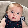 baby, infant, face, blue_eyes, curious, cushion, soft_texture, navy_blue_clothing, flower_pattern, child, portrait, close_up, indoor, cute, skin, head, person, young, expression, sitting