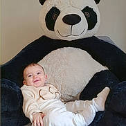 Lysana a rejoint le concours — aidez-le/la à gagner de superbes lots ! baby, infant, smiling, plush_toy, panda, stuffed_animal, soft_toy, indoor, cozy, child, cute, clothing, white_pants, sweater, happy, portrait, bed, fabric, toy, relaxed