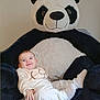 baby, infant, smiling, plush_toy, panda, stuffed_animal, soft_toy, indoor, cozy, child, cute, clothing, white_pants, sweater, happy, portrait, bed, fabric, toy, relaxed