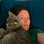 Jamie joined the competition — help win amazing prizes! person, cat, gray_tabby, indoor, couch, relaxing, close_up, portrait, feline, pet, companion, casual, green_shirt, resting, animal, cute, cozy, home, friendship, comfort