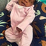 baby, infant, smiling, pink_onesie, cushion, patterned_fabric, sleeping, cozy, child, resting, indoor, cute, small_hands, soft_lighting, portrait, comfort, relaxation, happy, peaceful, person