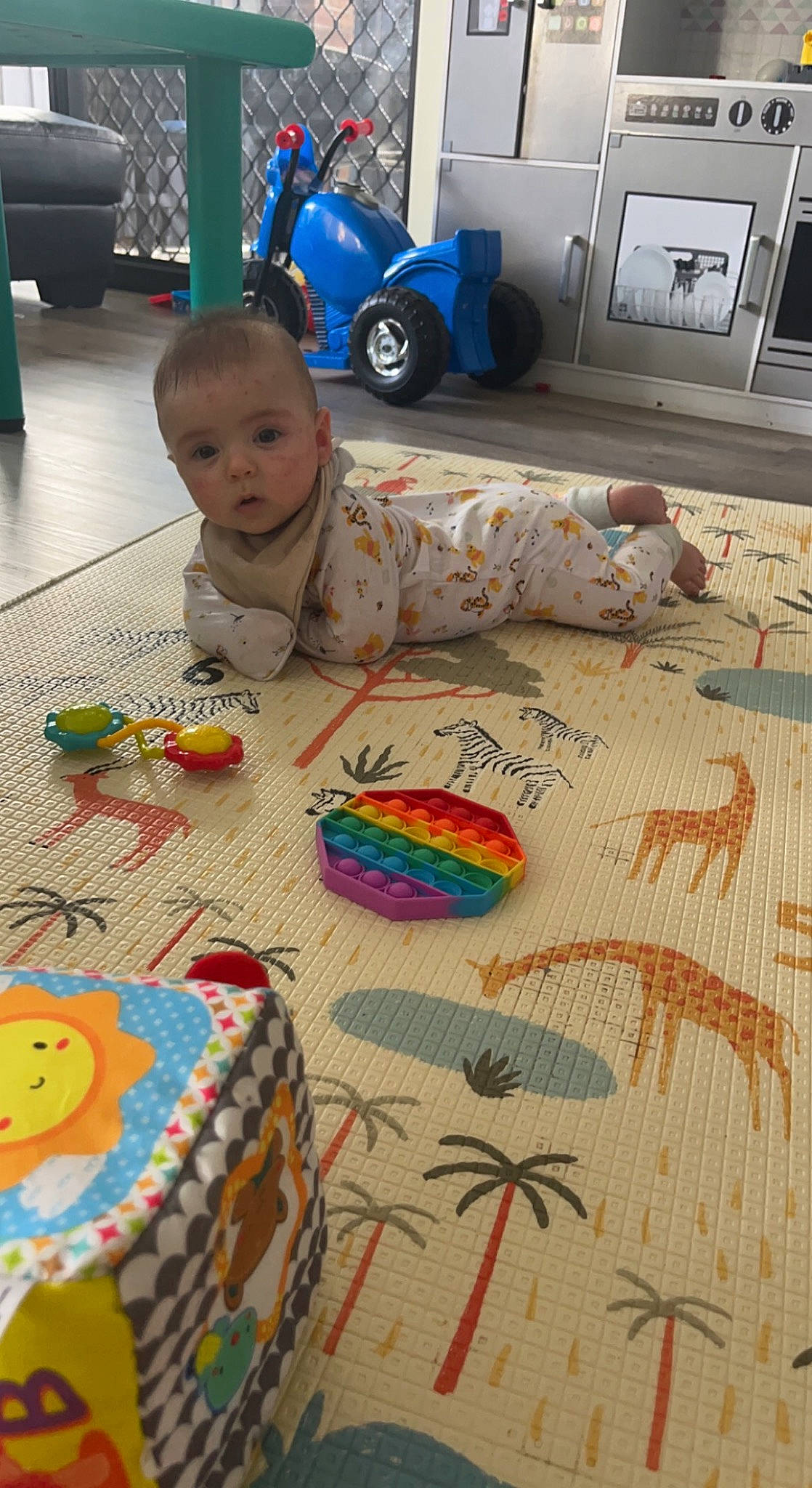Julian is registered to the contest to win money with this photo: art, baby, baby_toys, blue, carpet, child, floor, flooring, fun, linens, pattern, person, play, room, textile, tire, toddler, toy, visual_arts, wheel