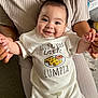 Damién joined the competition — help win amazing prizes! baby, smile, white_clothing, infant, happy, person, holding_hands, cute, child, sitting, indoor, adult_hands, tshirt_print, lumpia, food_illustration, young_child, portrait, face, cheerful, casual