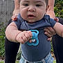 baby, child, pacifier, blue_shirt, denim_jeans, outdoor, garden, fence, plants, adult_hands, grass, sky, clouds, person, holding, cute, infant, portrait, casual_clothing, supporting