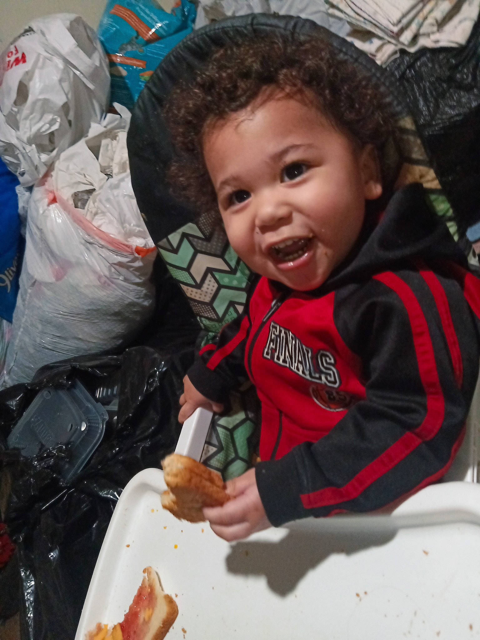 Darius is registered to the contest to win money with this photo: baby, baby_toddler_clothing, child, comfort_food, food, happy, ingredient, junk_food, laugh, mouth, person, plastic, plastic_bag, plate, sitting, sleeve, smile, t_shirt, tableware, thumb