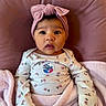 baby, infant, pink_headband, blanket, cushion, onesie, floral_pattern, indoor, cute, portrait, child, soft_texture, pink, cozy, young, sitting, face, wide_eyes, headwear, newborn