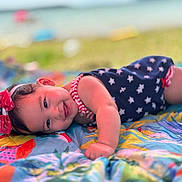 Reagan joined the competition — help win amazing prizes! baby, child, infant, smiling, outdoor, blanket, colorful, headband, bow, clothing, stars, grass, nature, portrait, lying_down, happy, cute, summer, daylight, playful