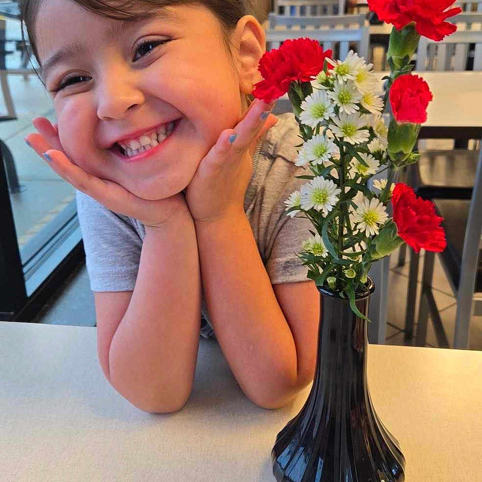 Isabella Ray Gonzales joined the competition — help win amazing prizes! diningtable, face, flower, flowerarrangement, flowerbouquet, furniture, head, ikebana, jar, person, petal, photography, plant, planter, portrait, pottedplant, pottery, rose, table, vase